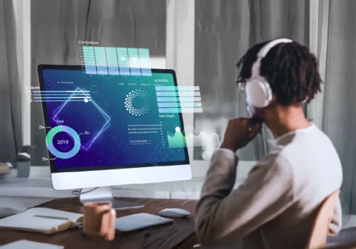 Person wearing headphones sits at a desk, analyzing futuristic digital graphs and data visualizations on a large desktop screen, representing advanced tracking and traceability technology.
