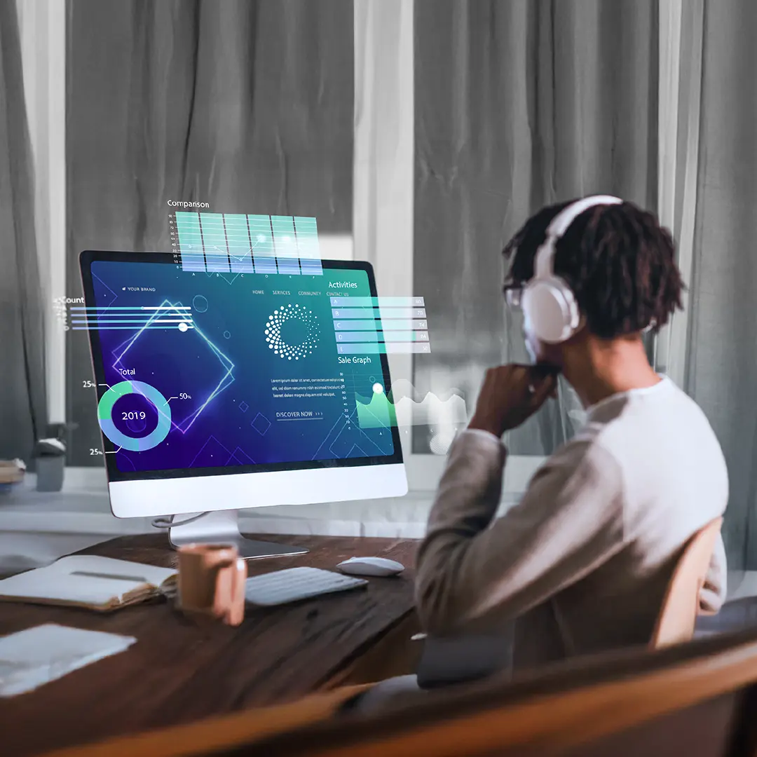 Person wearing headphones sits at a desk, analyzing futuristic digital graphs and data visualizations on a large desktop screen, representing advanced tracking and traceability technology.